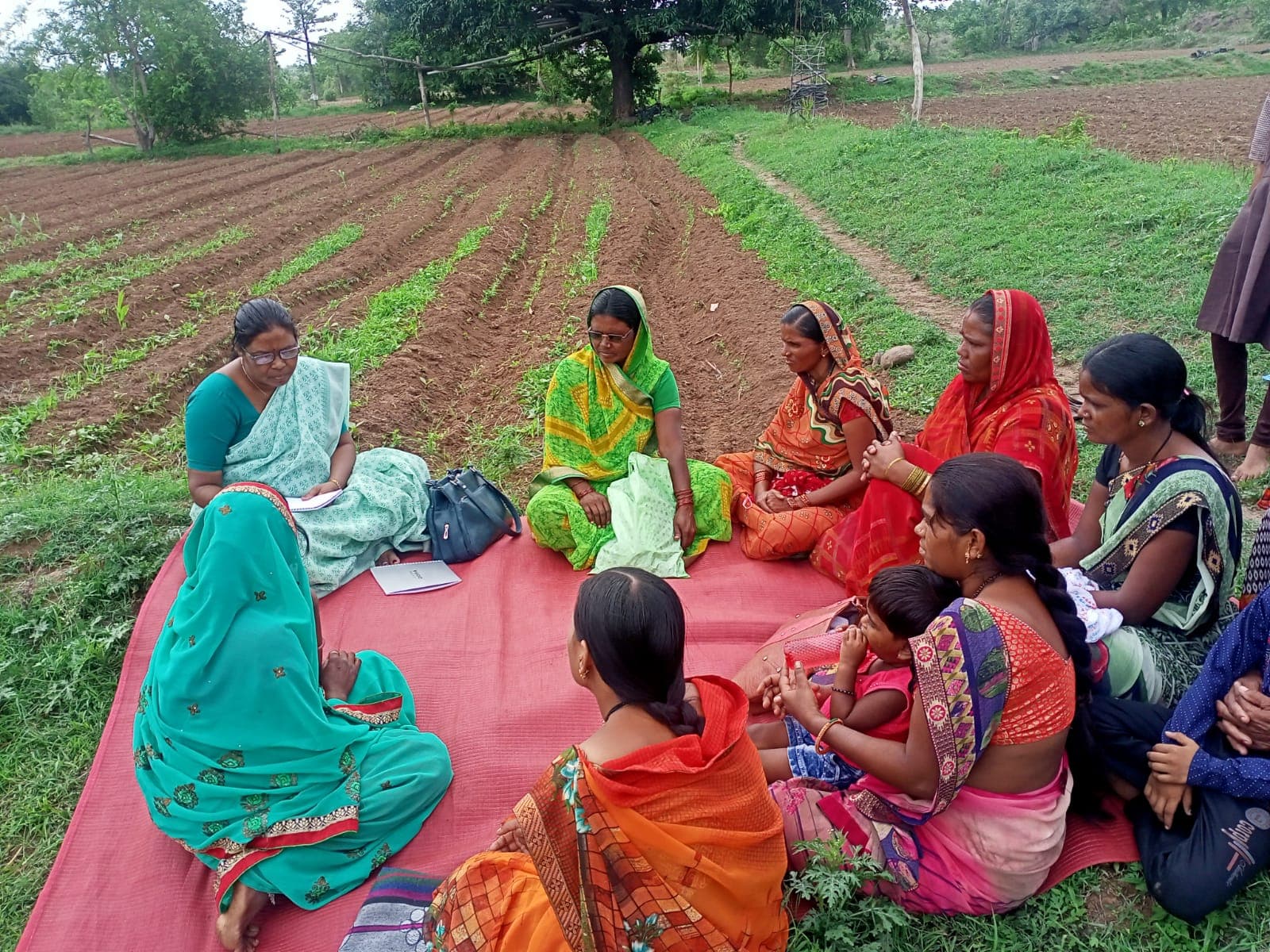 Women seated in a circle for a group discussion at the field's edge